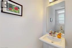 Pedestal sink with chrome faucet, illuminated by an overhead light fixture - 