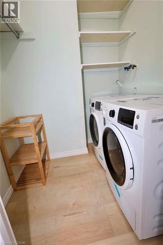 Dedicated laundry area featuring wood-finish flooring, built-in shelving, and a mounted clothing rod - 67 Valleyview Road Unit# 58, Kitchener, ON - Indoor Photo Showing Laundry Room