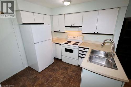 Kitchen featuring white cabinetry with black hardware, a stainless steel double-basin sink, light-toned countertops, a white electric range, and a white refrigerator - 67 Valleyview Road Unit# 58, Kitchener, ON - Indoor Photo Showing Kitchen With Double Sink