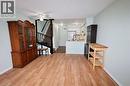 Open-concept living space featuring wood-finish flooring, a kitchen with white cabinetry and stainless steel appliances, and a staircase with dark wood railing - 67 Valleyview Road Unit# 58, Kitchener, ON  - Indoor Photo Showing Other Room 
