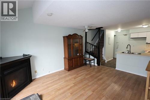 Living area featuring wood-finish flooring, light-toned walls, and a corner fireplace - 67 Valleyview Road Unit# 58, Kitchener, ON - Indoor With Fireplace