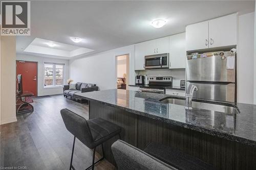 Contemporary kitchen featuring a large island with an undermount sink and bar seating, white cabinetry, and stainless steel appliances - 2635 William Jackson Drive Unit# 705, Pickering, ON - Indoor Photo Showing Kitchen With Stainless Steel Kitchen With Double Sink With Upgraded Kitchen