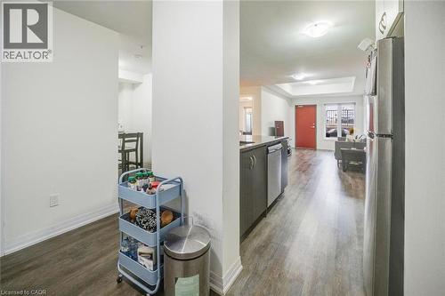Open concept living area featuring wood-finish flooring, a kitchen island with dark cabinetry, stainless steel appliances, and a red entry door - 2635 William Jackson Drive Unit# 705, Pickering, ON - Indoor