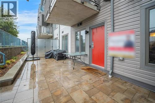 Spacious patio featuring a stone paver surface, a vibrant red entry door, horizontal siding, and a glass privacy screen - 2635 William Jackson Drive Unit# 705, Pickering, ON - Outdoor