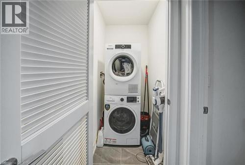 Dedicated laundry closet featuring a stacked washer and dryer, tile flooring, and louvered bifold doors - 2635 William Jackson Drive Unit# 705, Pickering, ON - Indoor Photo Showing Laundry Room
