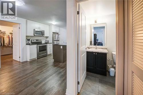 Modern kitchen featuring white cabinetry, stainless steel appliances, and a dark wood-finish island - 2635 William Jackson Drive Unit# 705, Pickering, ON - Indoor Photo Showing Kitchen