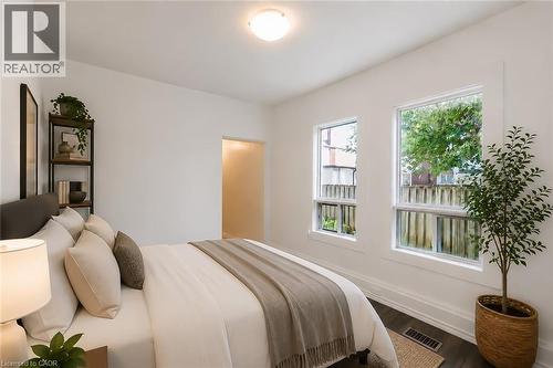 Bedroom featuring two bright windows, dark wood-finish flooring, white baseboards, and a flush-mount ceiling light - 87 Lancaster Street W, Kitchener, ON - Indoor Photo Showing Bedroom