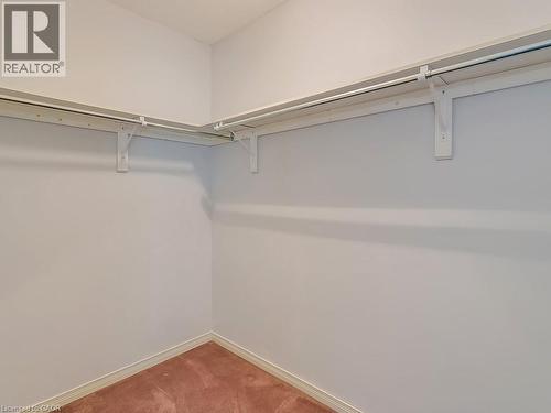 Walk-in closet featuring white painted walls, a textured ceiling, a built-in shelf system with hanging rods, and carpet flooring - 1310 Blanshard Drive, Burlington, ON - Indoor With Storage