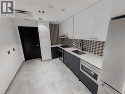 Contemporary kitchen featuring light gray tile flooring and a geometric tiled backsplash - 