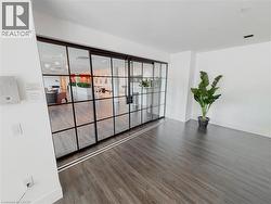 Spacious room featuring wood-finish flooring, white walls, and a large grid-patterned glass sliding door - 