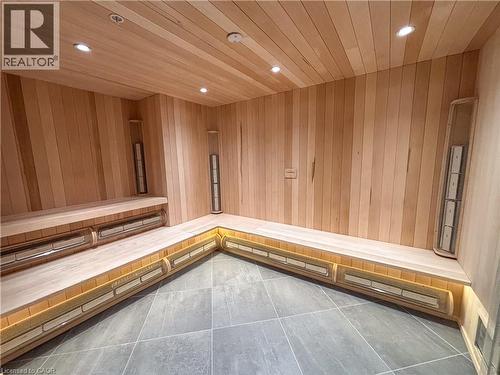 Custom-built sauna with light wood paneling, multi-level bench seating, built-in heaters, recessed ceiling lighting, and large format tile flooring - 15 Wellington Street S Unit# 1909, Kitchener, ON - Indoor Photo Showing Other Room