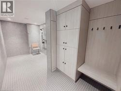 Spacious shower area featuring light grey textured wall tiles and small square floor tiles - 