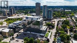 Modern glass-front office building featuring a connecting skybridge, a rooftop green space, and surrounding urban infrastructure with high-rise residential buildings - 