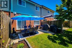 Fenced backyard featuring a paver patio, mature lawn, and planting beds - 
