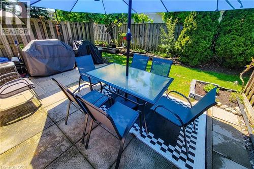 Expansive patio area featuring large paver stones, a wooden privacy fence, and a vibrant green lawn - 232 Stonehenge Drive Unit# 2, Ancaster, ON - Outdoor With Deck Patio Veranda