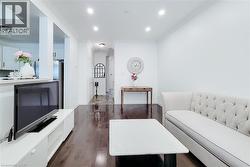 Open-concept living area featuring rich wood-finish flooring, recessed lighting, crown molding, and a partial wall separating spaces - 