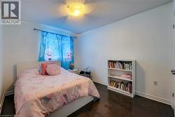 Bedroom featuring wood-finish flooring, white baseboards, and a contemporary ceiling light fixture - 
