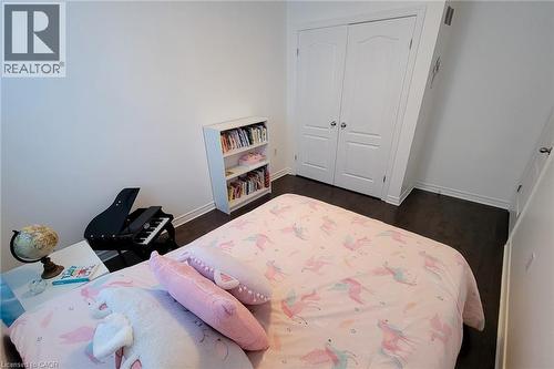Spacious room featuring wood-finish flooring, white baseboards, and a built-in double-door closet with paneling - 232 Stonehenge Drive Unit# 2, Ancaster, ON - Indoor Photo Showing Bedroom