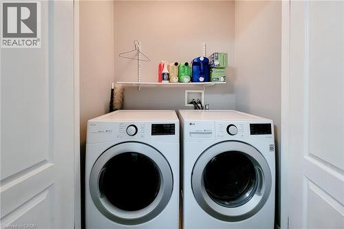Dedicated laundry area featuring a front-load washer and dryer, a single wall-mounted shelf, and neutral wall paint - 232 Stonehenge Drive Unit# 2, Ancaster, ON - Indoor Photo Showing Laundry Room