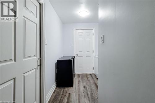 Hallway featuring wood-finish flooring, white paneled doors, and contemporary overhead lighting - 232 Stonehenge Drive Unit# 2, Ancaster, ON - Indoor Photo Showing Other Room