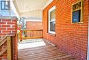 Inviting covered porch featuring brick columns and facade, wood deck flooring, and a white screen door - 304 Park Street, Dundas, ON  - Outdoor With Deck Patio Veranda With Exterior 