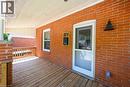 Inviting covered porch featuring brick columns and facade, wood deck flooring, and a white screen door - 304 Park Street, Dundas, ON  - Outdoor With Deck Patio Veranda With Exterior 