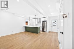 Kitchen featuring a peninsula, freestanding refrigerator, white cabinets, light wood-style flooring, and green cabinets - 