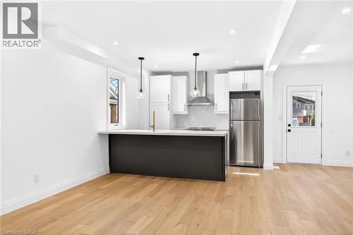Kitchen with stainless steel appliances, a peninsula, light wood-type flooring, decorative light fixtures, and dual tone cabinetry - 304 Park Street, Dundas, ON - Indoor Photo Showing Kitchen With Upgraded Kitchen