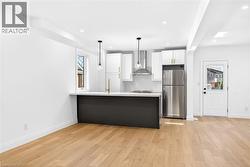 Kitchen featuring a peninsula, light countertops, white cabinetry, freestanding refrigerator, and light wood-type flooring - 