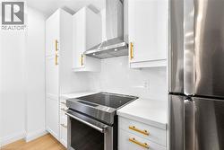 Kitchen featuring stainless steel appliances, white cabinets, light wood-style floors, tasteful backsplash, and light stone counters - 