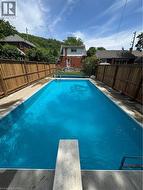 Rectangular swimming pool featuring a diving board, surrounding concrete patio, and privacy fencing - 