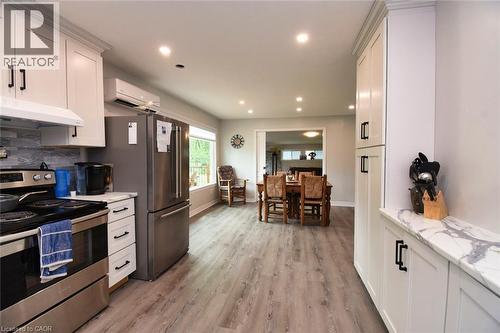Contemporary kitchen featuring white cabinetry, stainless steel appliances, a tile backsplash, and light wood-finish flooring - 5 Ralph Street, Turkey Point, ON - Indoor Photo Showing Kitchen With Upgraded Kitchen