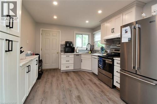Kitchen featuring wood-finish flooring, white cabinetry with dark hardware, stainless steel appliances, and recessed lighting - 5 Ralph Street, Turkey Point, ON - Indoor Photo Showing Kitchen