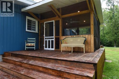 Expansive outdoor wood deck with multiple steps, extending to a screened porch featuring natural wood framing, recessed lighting, and a ceiling fan - 5 Ralph Street, Turkey Point, ON - Outdoor With Deck Patio Veranda With Exterior