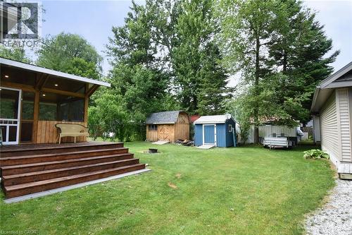 Expansive backyard featuring a screened porch with a wood-finish ceiling and recessed lighting, a multi-tiered wood-finish deck, two storage sheds, and mature trees - 5 Ralph Street, Turkey Point, ON - Outdoor With Deck Patio Veranda