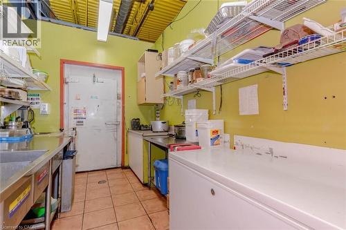 Commercial kitchen space featuring a large walk-in cooler, extensive stainless steel counters, and durable tile flooring - 1035 Brant Street Unit# 1C, Burlington, ON 