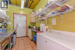 Commercial kitchen space featuring a large walk-in cooler, extensive stainless steel counters, and durable tile flooring - 