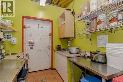 Commercial kitchen space featuring a walk-in cooler, stainless steel workstations, tiled flooring, wood-finish upper cabinetry, and wire shelving - 1035 Brant Street Unit# 1C, Burlington, ON 