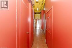 Hallway with tile flooring, exposed ceiling infrastructure, fluorescent lighting, and multiple panel doors - 