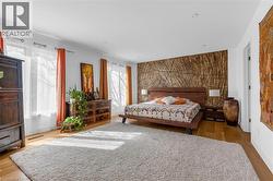 Spacious bedroom featuring wood-finish flooring, recessed lighting, and ample natural light from multiple windows - 