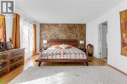 Bedroom featuring a prominent wood grain accent wall and light wood-finish flooring - 
