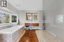 Spacious bathroom featuring a built-in soaking tub with pebble tile surround and expansive bay window - 