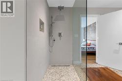 Walk-in shower with pebble tile flooring, tiled walls, a built-in niche, and a rain shower head - 