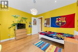 Vibrant room with wood-finish flooring, bright yellow walls, and a contemporary ceiling fixture - 