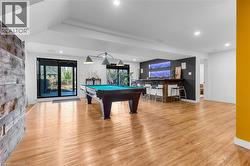 Spacious recreation room featuring wood-finish flooring, recessed lighting, and a built-in bar with pendant lighting - 