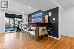 Entertainment area featuring wood-finish flooring, a built-in bar with a stone countertop, and brick-textured wall accents with integrated lighting - 