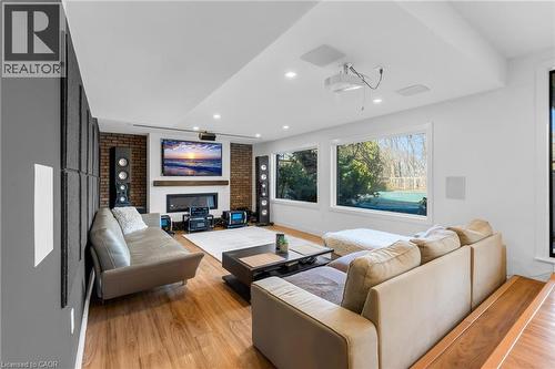 Spacious entertainment room featuring wood-finish flooring, a brick-faced fireplace with a recessed hearth, and a wood mantel - 39 Hilts Drive, Stoney Creek, ON - Indoor Photo Showing Living Room With Fireplace