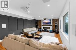Living area featuring a fireplace with brick surround, wood mantel, and integrated television - 