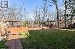Expansive backyard featuring a multi-level wood-finish deck, a built-in gazebo, and a pergola structure - 