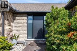 Exterior entry featuring a dark gray door with vertical window panels and stacked stone siding - 
